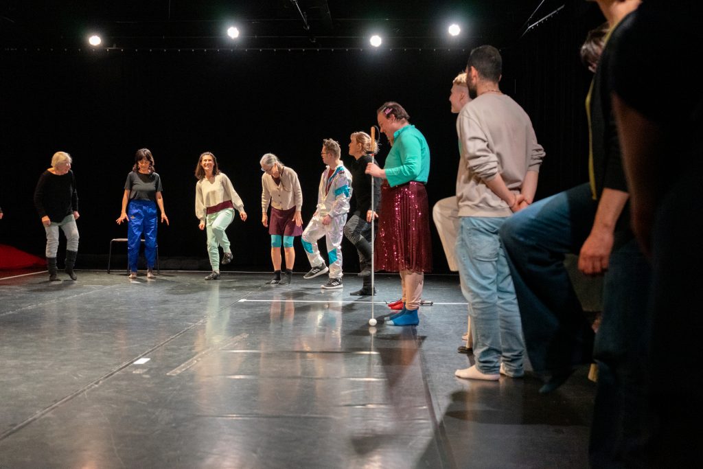 Eine Gruppe folgt der Workshopleiterin mit Tanzbewegungen in einem großen Raum