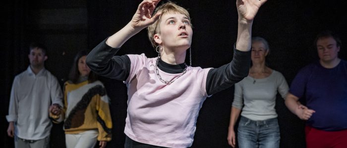 Anno im Vordergrund, der Blick zu den erhobenen Händen, die Finger stupsen imaginäre Luftblasen weg. Im Hintergrund stehen Lukas, Keiko, Lilian und Sarah in einer Reihe und schauen zu.